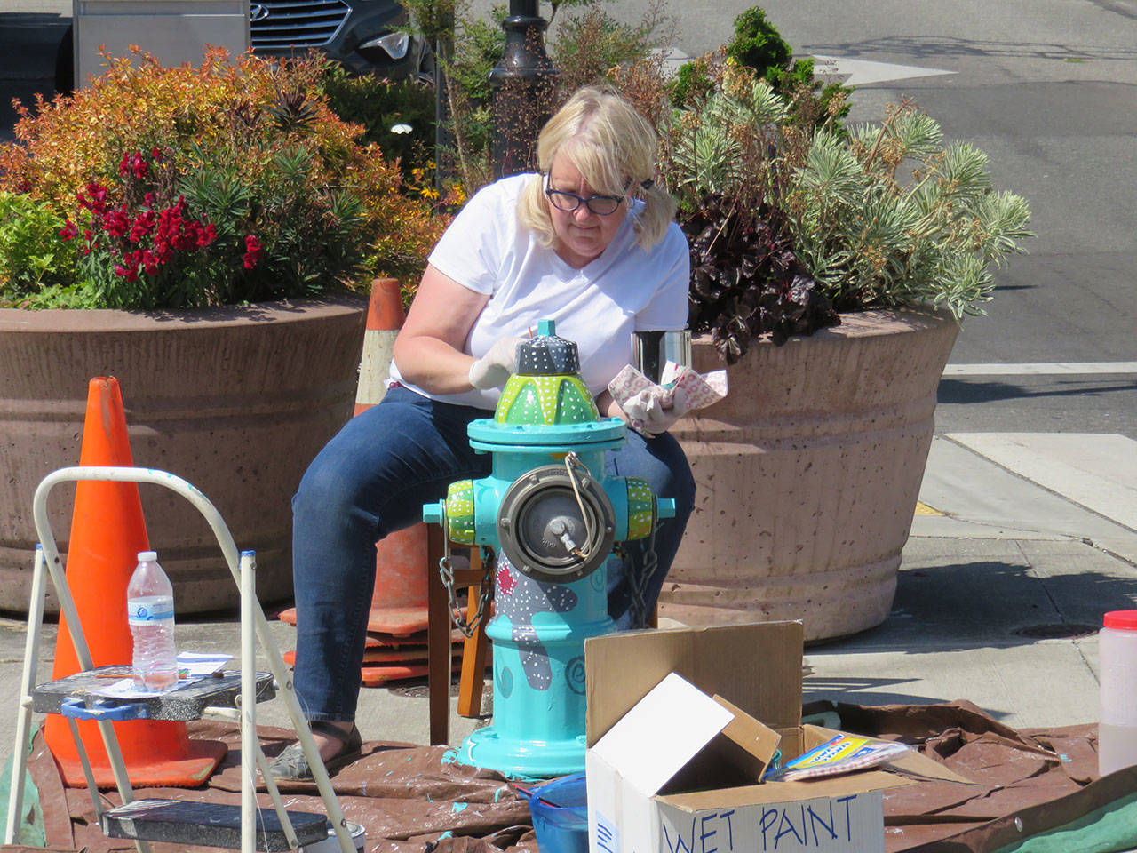 Before she moves to Santa Fe, Lizbeth Cort paints the first fire hydrant as a test for an upcoming Oak Harbor Arts Commission project. Photo provided by the Oak Harbor Arts Commission