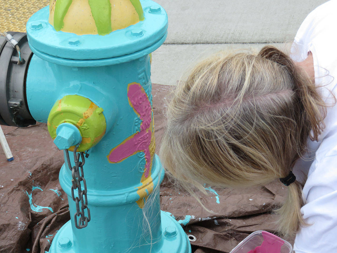 Artist Lizbeth Cort leans into the fire hydrant she painted on July 20. Photo provided by the Oak Harbor Arts Commission.