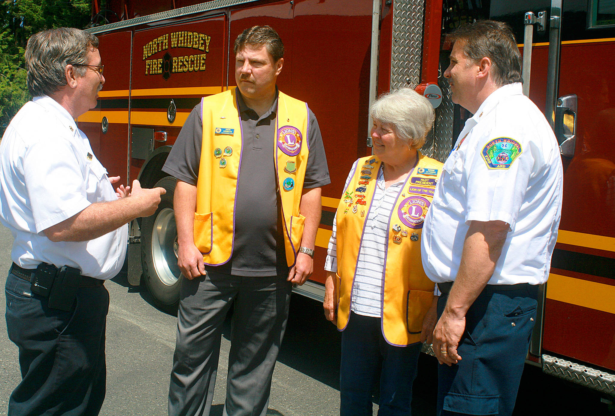 From left, Fire Chief Mike Brown, North Whidbey Lions President Jack Peebles, past-president Bonnie LaForest and Deputy Fire Chief Mark Kirko discuss their new partnership Wednesday at the VFW. North Whidbey Lions gave North Whidbey Fire and Rescue $10,000 to kick off its legacy project. Photo by Daniel Warn/Whidbey News-Times
