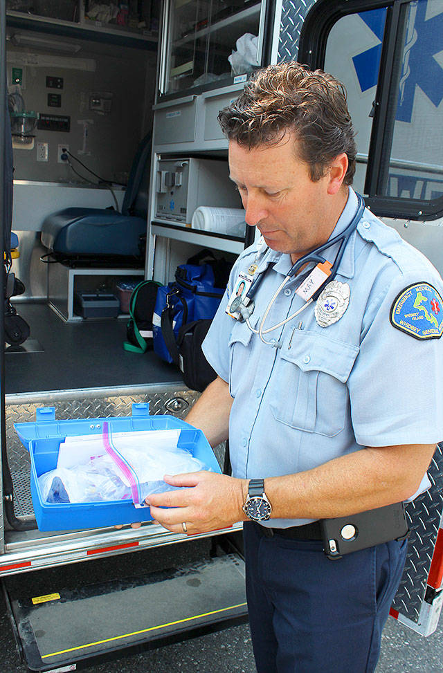 WhidbeyHealth EMS paramedic Robert May looks over a kit used on patients suffering heart attacks.                                By Patricia Guthrie/Whidbey News-Times