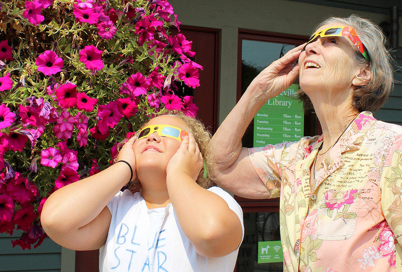 Kayla Cooks and her great-grandmother Barbara Fournier try out glasses they’ll be using in Oregon during Monday’s 2017 Total Solar Eclipse. The special glasses were given out as part of an informational talk at Coupeville Library. Photo by Patricia Guthrie/Whidbey News-Times