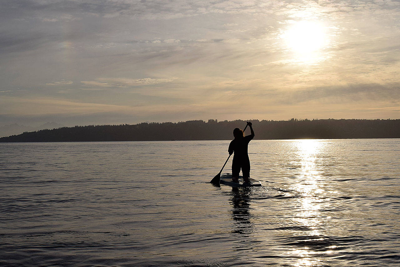 Kyle Jensen / The Record — Aja Stewart paddles out into Puget Sound to practice yoga and meditate.