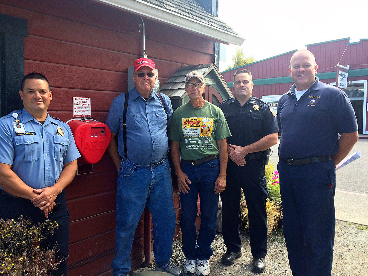 From left, lead paramedic Chris Tumblin with WhidbeyHealth-EMS, Mike Dessert and Dale Folkestad of Coupeville Festival Association, Deputy Marshal Leif Haugen of the Coupeville Marshal’s Office and Deputy Chief Charlie Smith of Central Whidbey Island Fire and Rescue stand by one of three AEDs installed around town. Photo provided