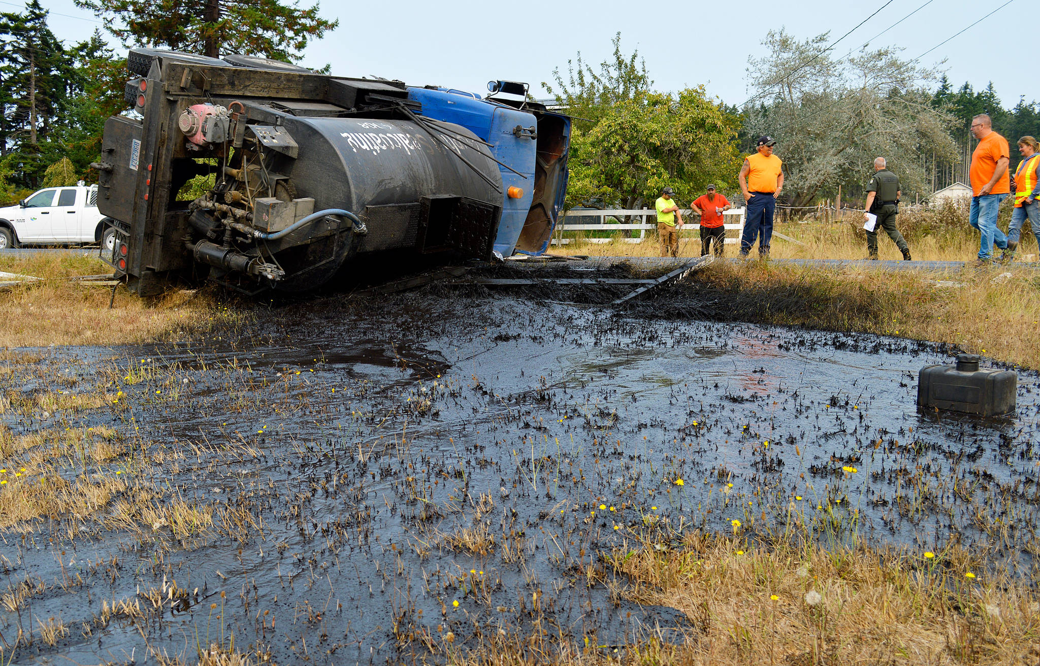 Asphalt sealcoating is spread across a field near Libbey Road after a truck containing it turned on its side. The driver said he lost brakes as he came off of West Beach Road. Photo by Laura Guido/ Whidbey News-Times