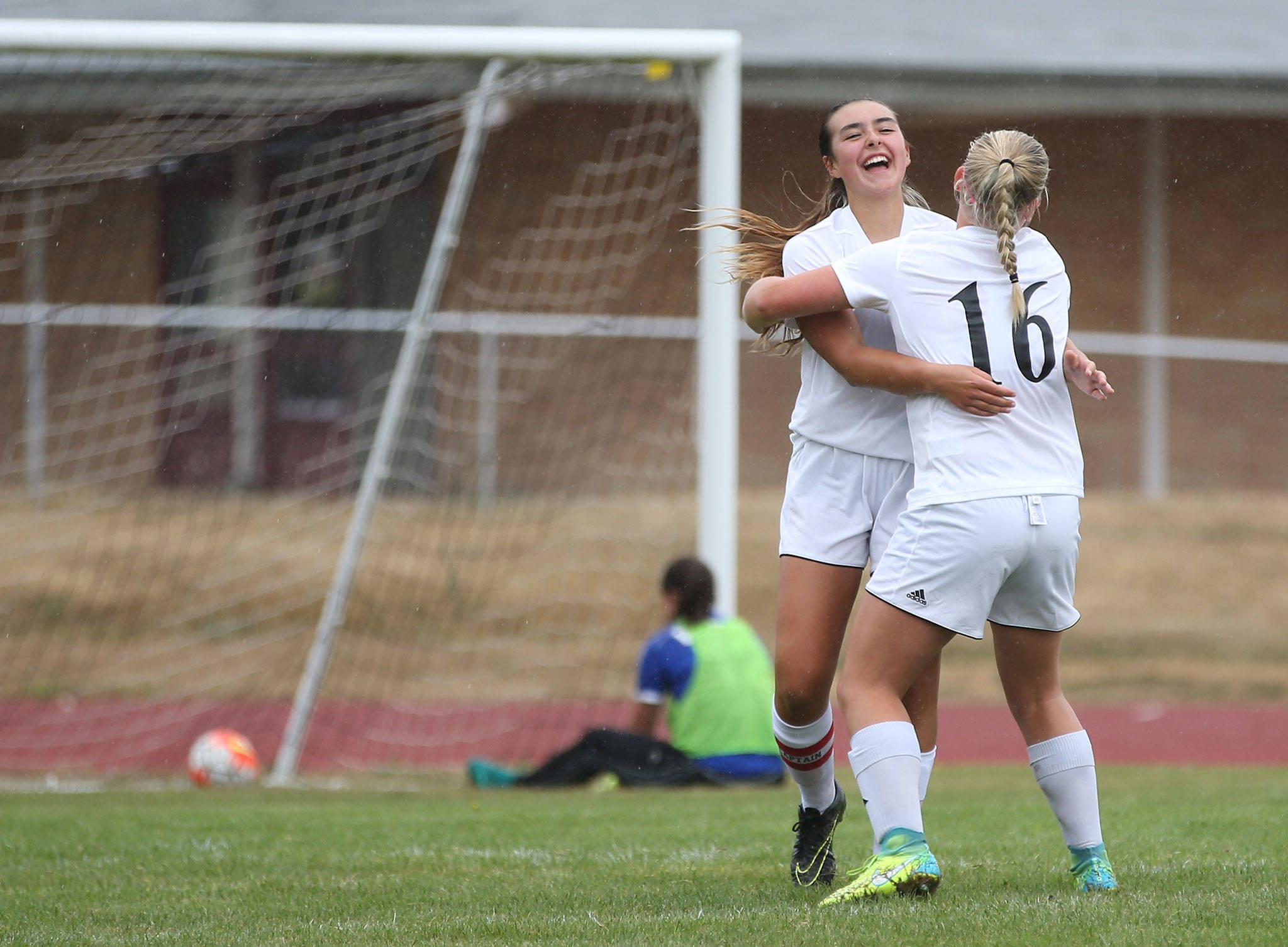 Lauren Bayne celebrates her long-distance goal with Avalon Renninger (16) as the Bellevue Christian goalkeeper can only look at the ball in the net. (Photo by John Fisken)
