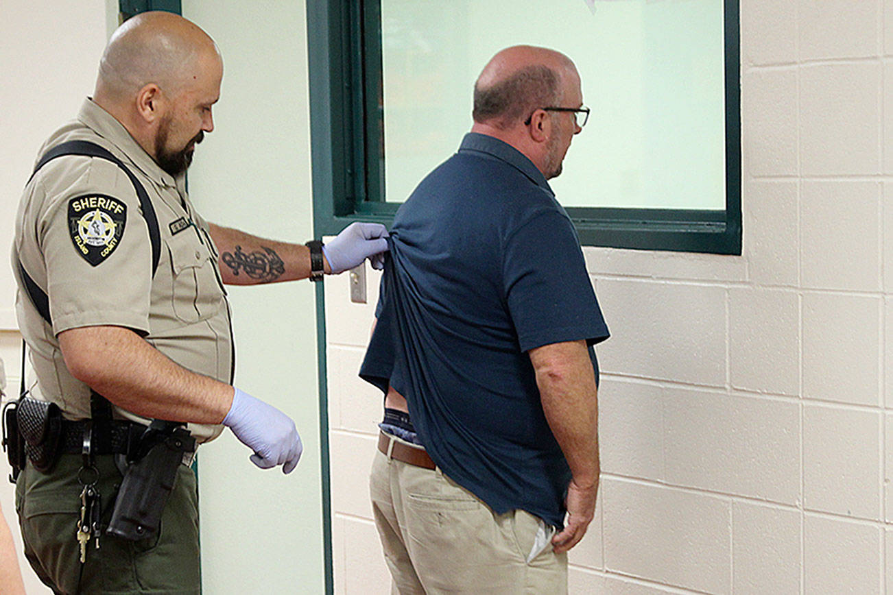Photo by Jessie Stensland / Whidbey News-Times                                Corrections deputies Pam McCarty and Gerald Adams process a man during a booking Thursday morning at the Island County Jail.