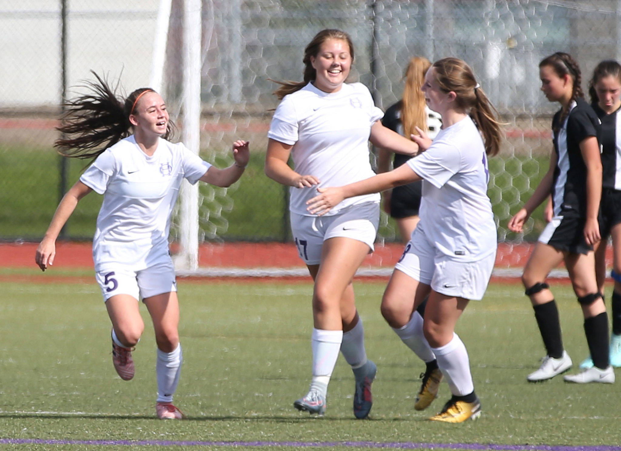 Natalie Plush, center, celebrates her goal with Aiden Anderson (5) and Peyton Rhyne. (Photo by John Fisken)