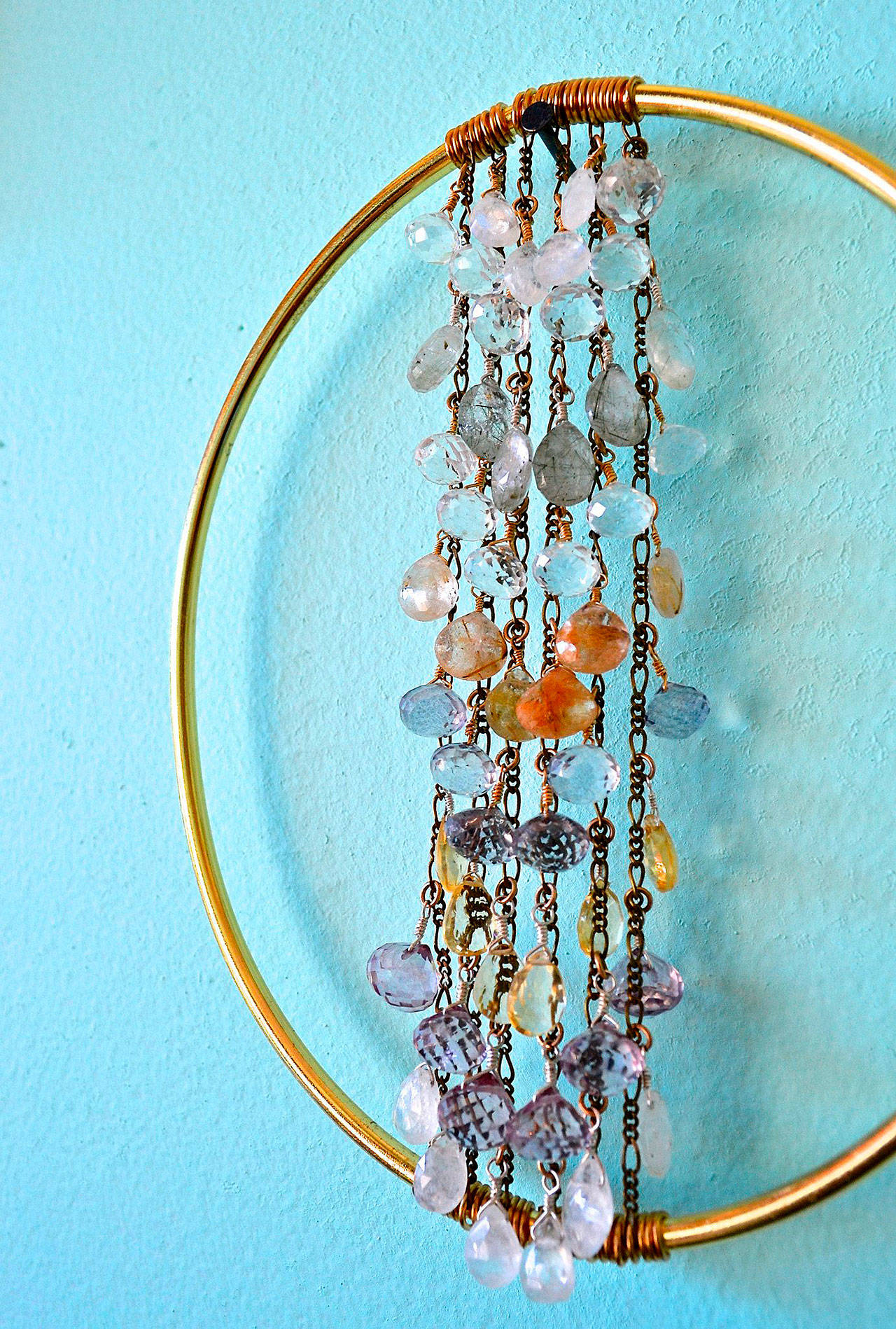 Alexa Allamano photo — Allamano makes home decor in addition to jewelry. In this piece, 52 gemstones are tethered to vertical chains and suspended in the center of a brass oval.