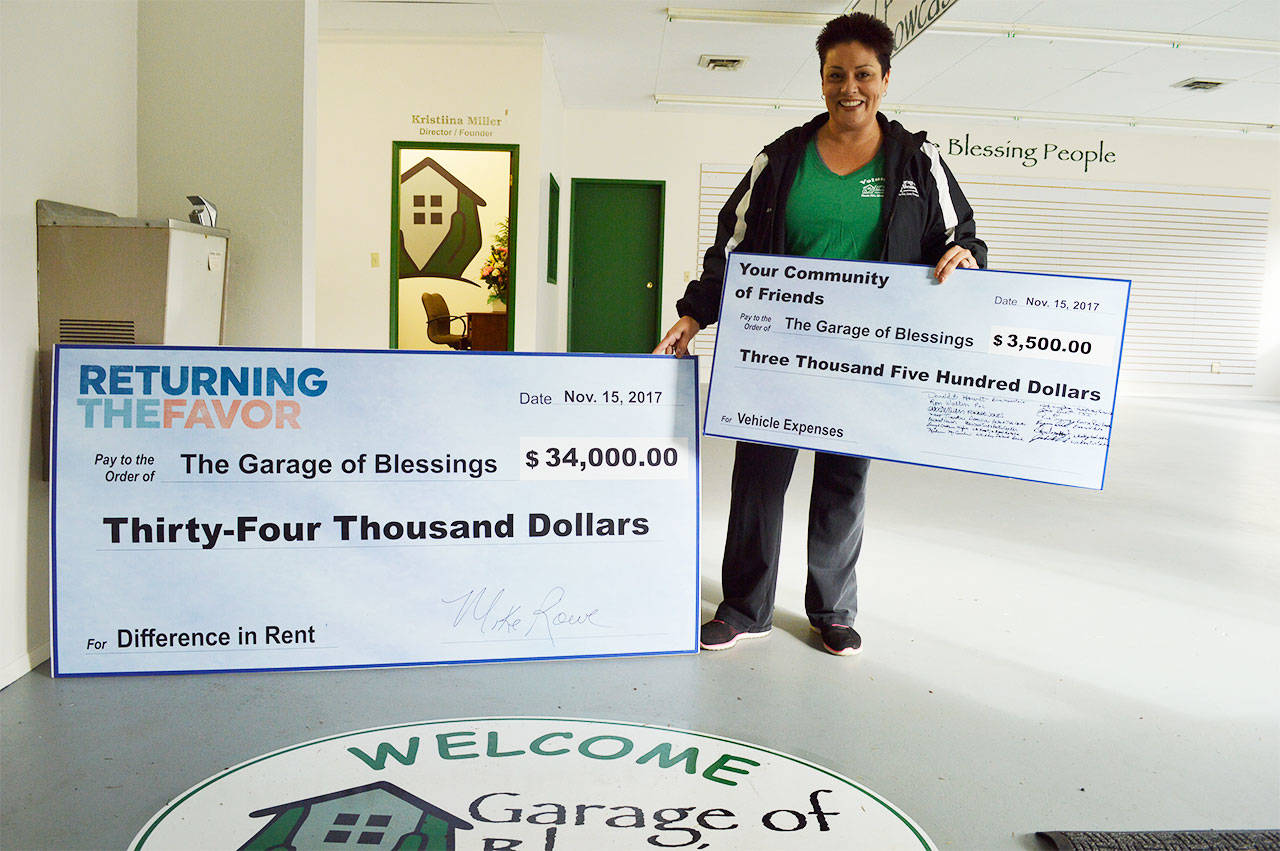 Kristiina Miller holds up two large checks she received during filming of “Returning the Favor,” a new show on Facebook with Mike Rowe. Miller’s Garage of Blessings will be featured on the show in February. Photo by Laura Guido/Whidbey News-Times