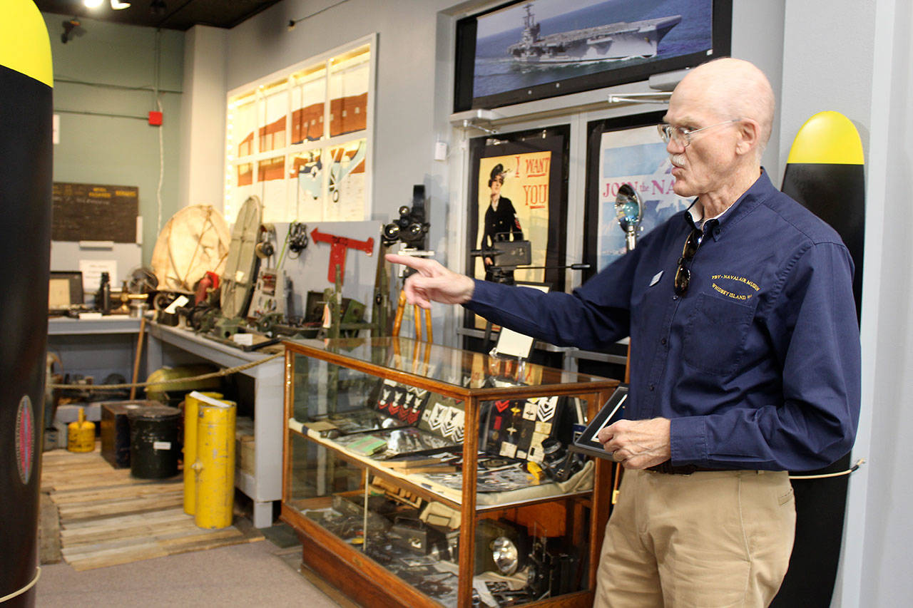 Wil Shellenberger, president of the PBY Museum Foundation, points to a wall display of newspaper from the WWII era. Photo by Patricia Guthrie/Whidbey News-Times