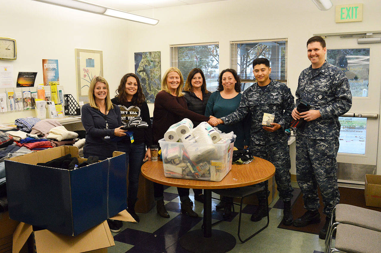 From the left, Carolyn Pence, Malissa Taylor, Joanne Pelant, Beth Plush, Tiffany Wheeler-Thompson, Seaman Ryan Breeden and Petty Officer First Class Rob Stuart. Breeden and Stuart ran drives from their squadron, VAQ-129, for toiletries and clothing for the county Housing Support Center. Photo by Laura Guido/Whidbey News-Times