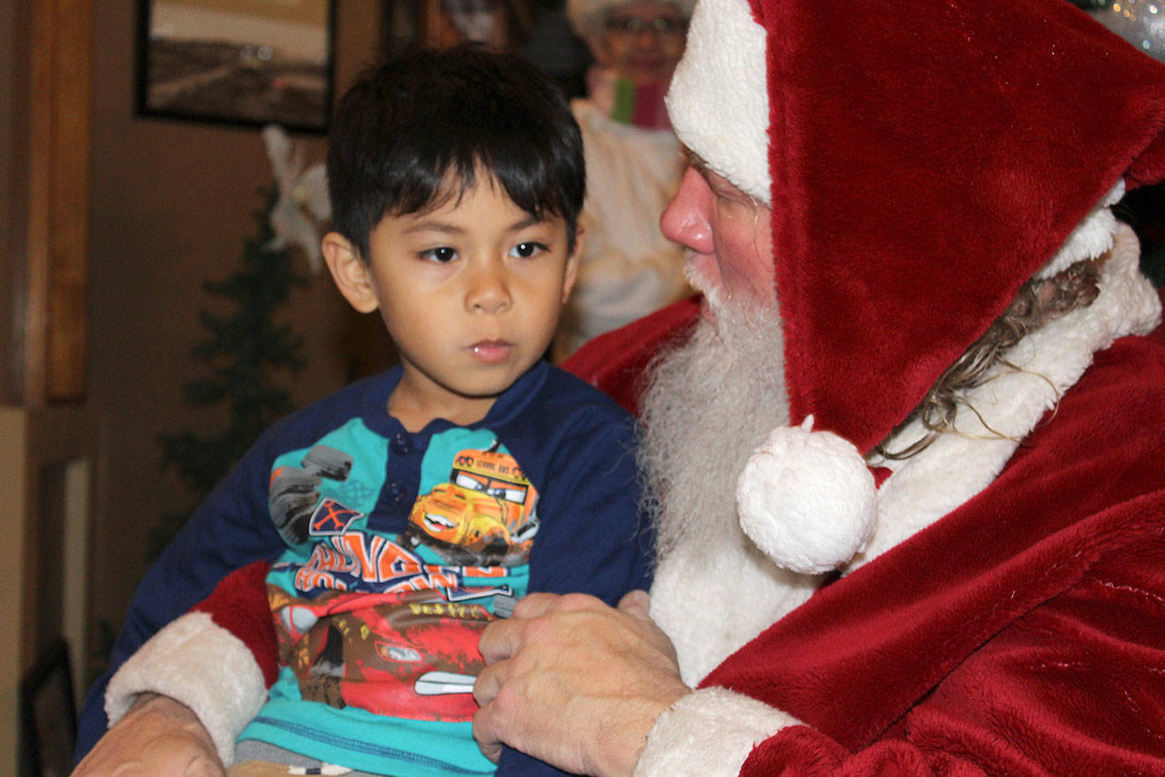 Arjay Andal looks a little perplexed as Santa Claus asks a few questions during Saturday’s “Meet Santa” event for families following the annual Oak Harbor tree lighting ceremony. Santa has more meet and greets through Dec. 23. Photos by Patricia Guthrie/Whidbey News-Times