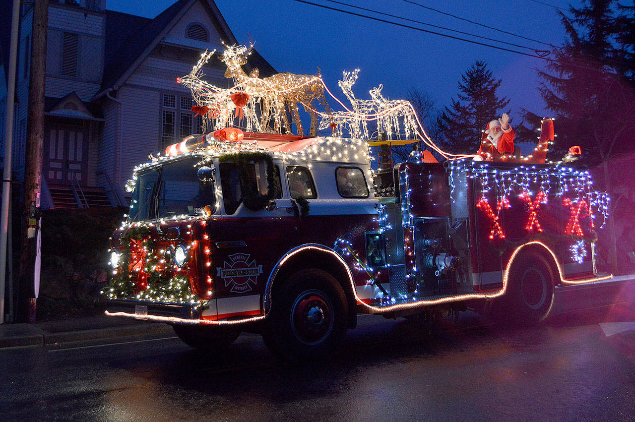 Fire Commissioner Paul Messner waves as a lighted fire truck takes him through the Greening of Coupeville Parade route Saturday. Photo by Megan Hansen/Whidbey News Group