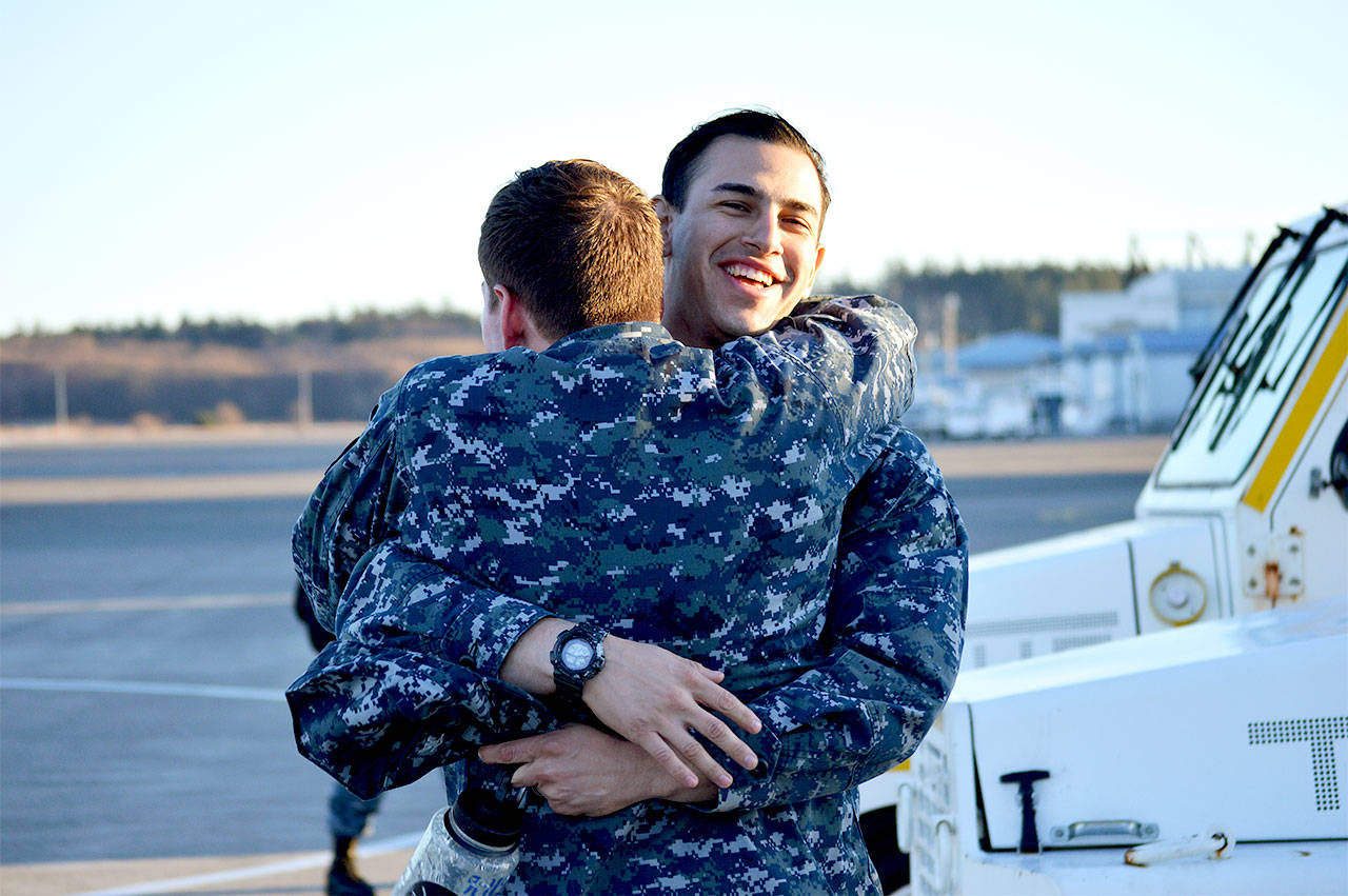 Jose Kuder, petty officer third class, is welcomed back by JJ Hughes during the homecoming for electronic attack squadron 142 Tuesday. Photo by Laura Guido/Whidbey News-Times