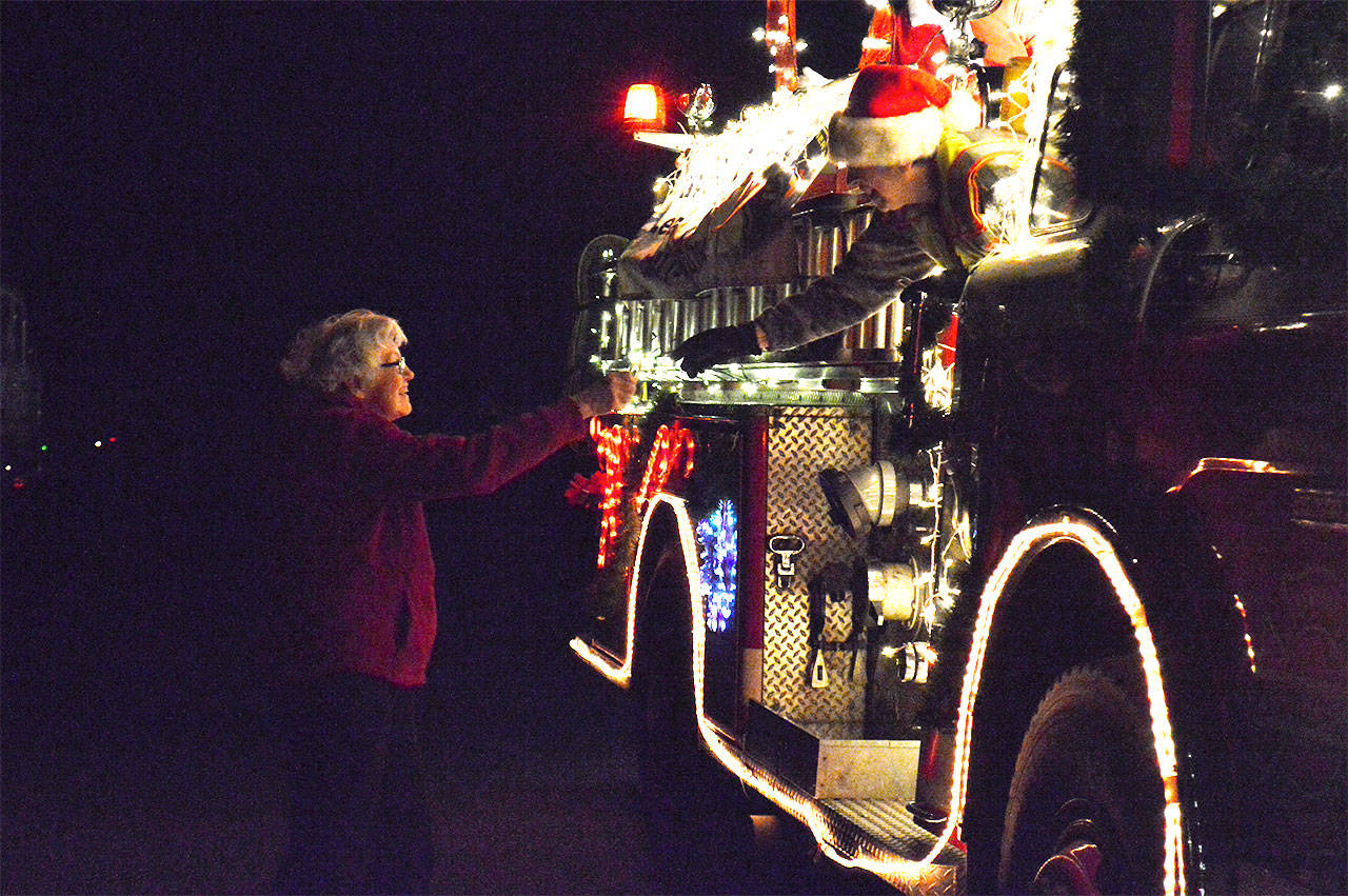 Shirley Bauder gets a candy cane from Sue Hartin, the lead elf with Central Whidbey Fire’s Santamobile Wednesday night near Lagoon Point. Photo by Laura Guido/Whidbey News-Times