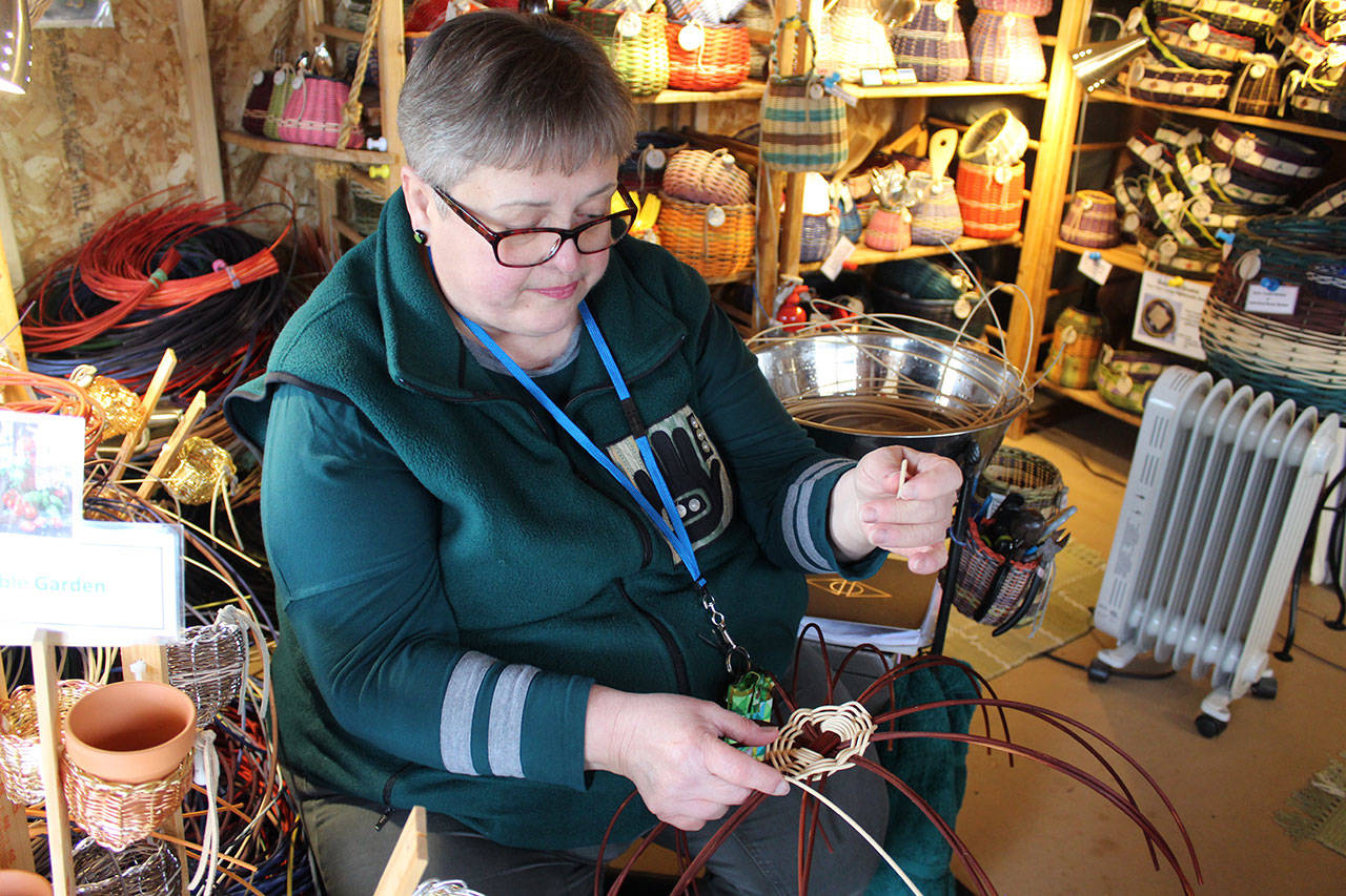 Reggie Kastler weaves a basket inside her Oak Harbor studio surrounded by her colorful creations. She’s made baskets for 30 years and also hand dyes the natural round reed. Photos by Patricia Guthrie/Whidbey News-Times