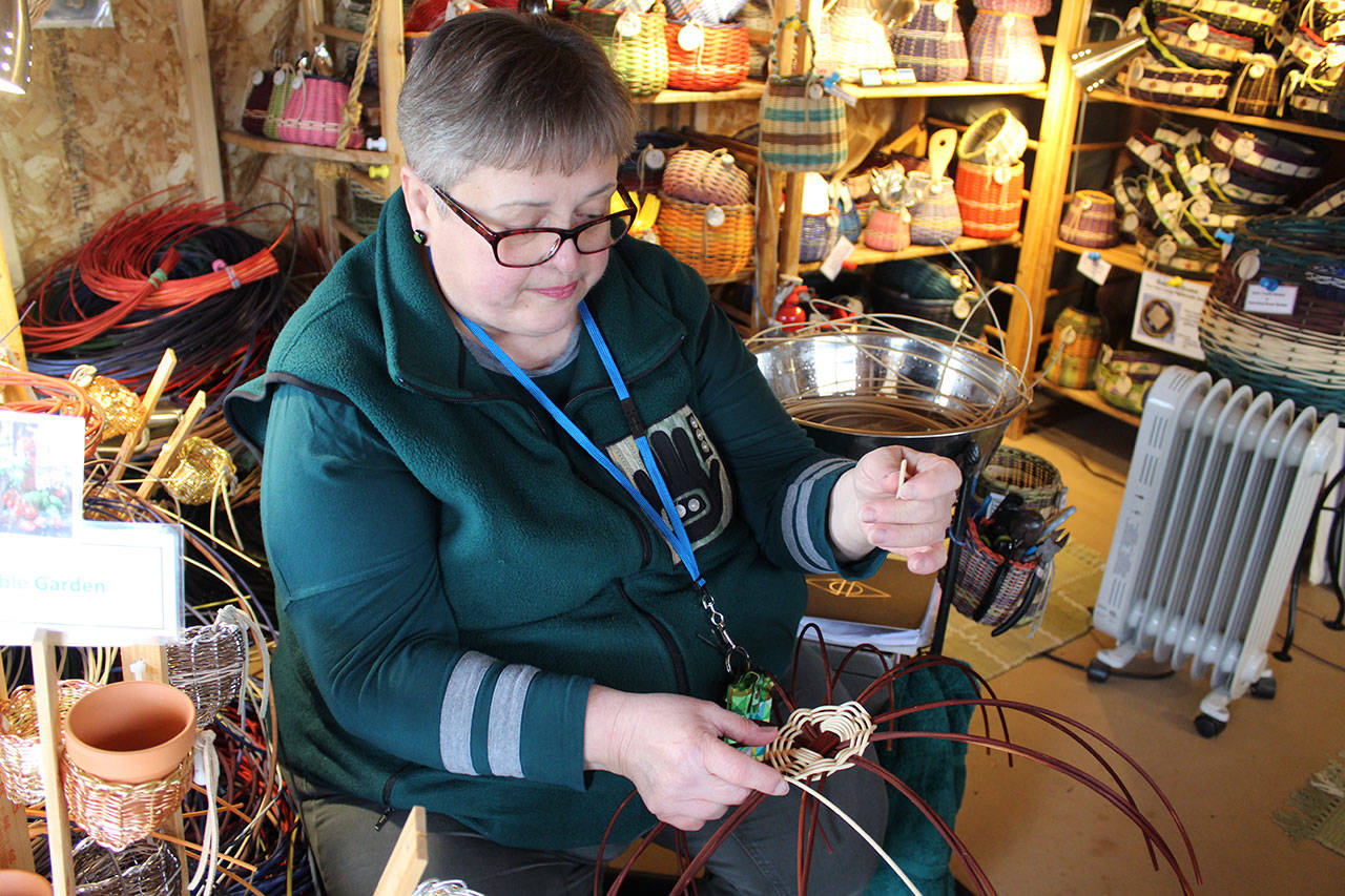 Reggie Kastler weaves a basket inside her Oak Harbor studio surrounded by her colorful creations. She’s made baskets for 30 years and also hand dyes the natural round reed. Photos by Patricia Guthrie/Whidbey News-Times