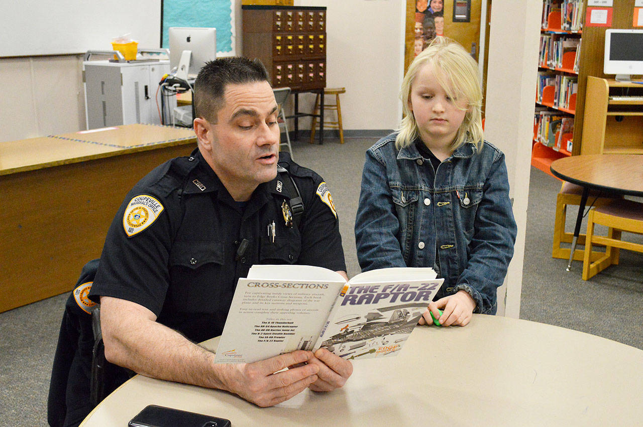 Deputy Marshal Leif Haugen reads to second grader Colby Terry in the library of Coupeville Elementary School. Haugen is part of the recently launched “Bigs with Badges” program at Big Brother Big Sisters that pairs children in the community with law enforcement officers. Photo by Laura Guido/Whidbey News-Times