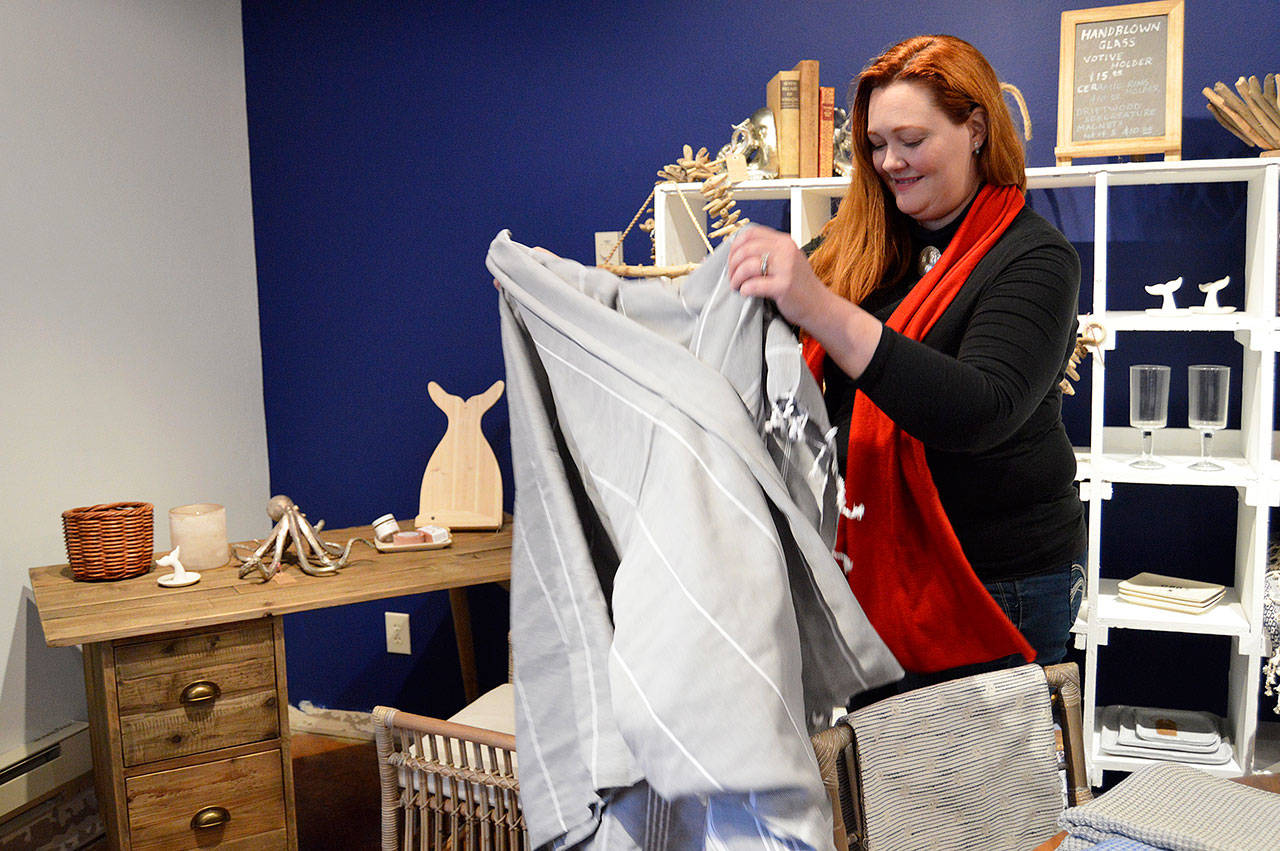Photos by Megan Hansen/Whidbey News-Times                                Mikel Peabody folds an imported linen at her new interior design shop Seaside & Sylvan, located at the Greenbank Farm.