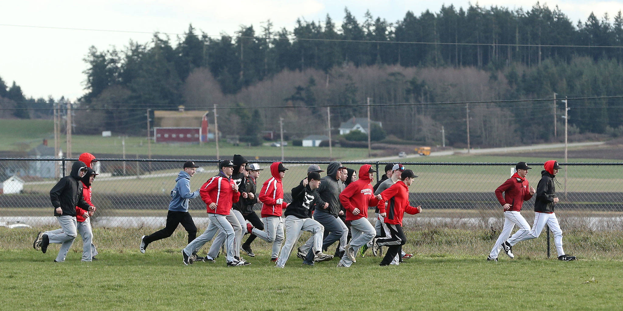 The Coupeville High School baseball team takes a lap around the field to get warmed up for the first day of practice Monday. (Photo by John Fisken)