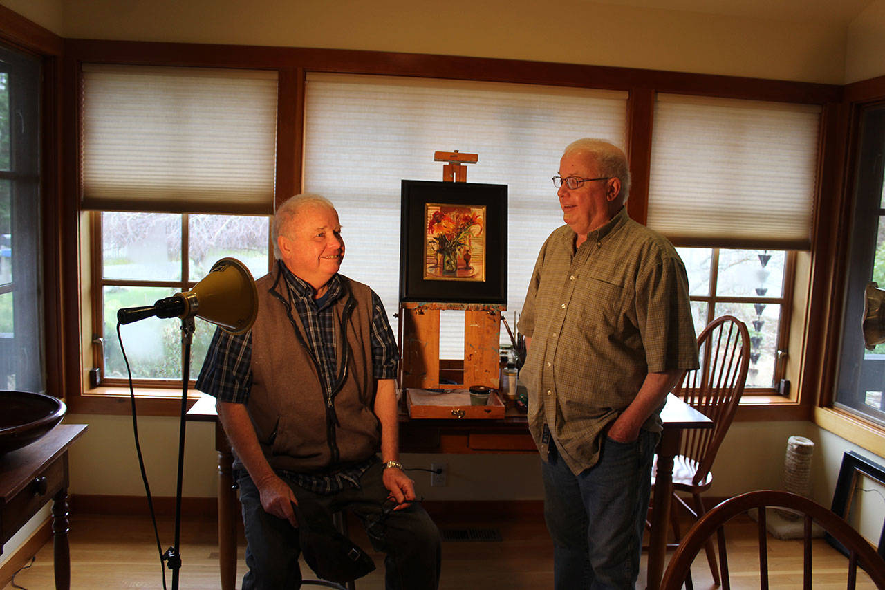 Twin brothers Dan and Mike Burroughs are both artists but with different styles. Mike (left) does ink and watercolor sketches and Dan paints with oils. Between them is one of Dan’s paintings. Photo by Patricia Guthrie/Whidbey News-Times