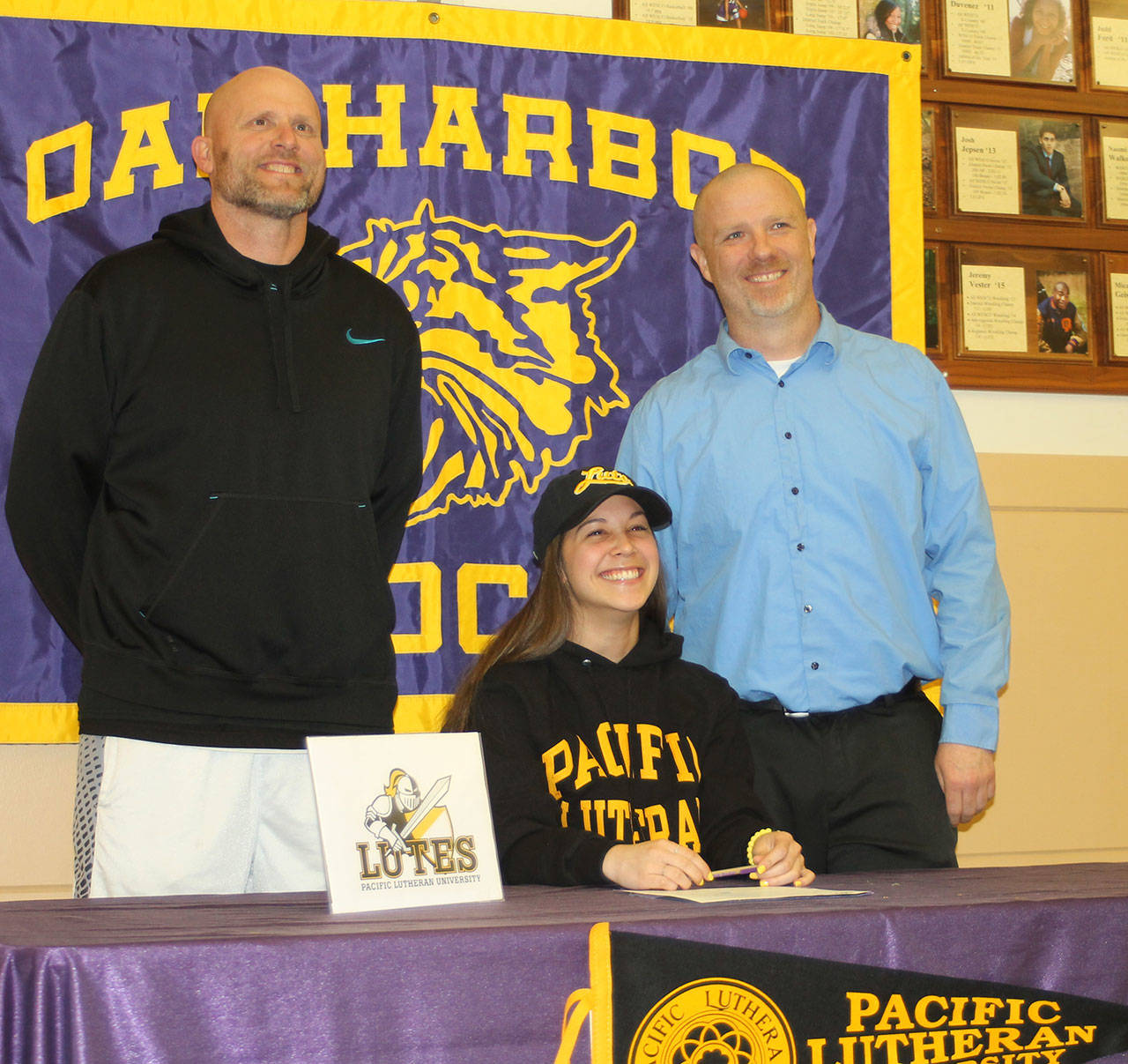 Flanked by track coaches Jay Turner (left) and Mike Fisher, Jenna Cooley signs a letter of intent to attend Pacific Lutheran University. (Photo by Jim Waller/Whidbey News-Times)