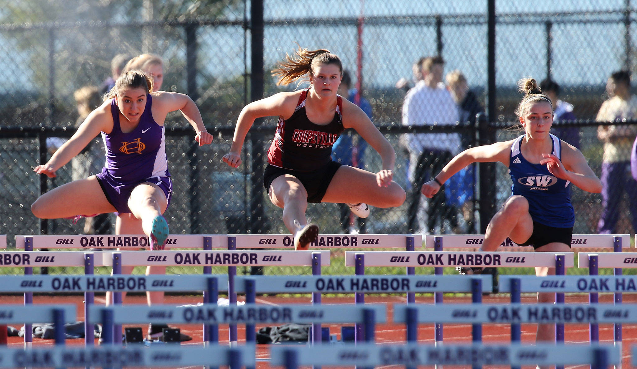 Oak Harbor’s Samantha Hines, left, Coupeville’s Lindsey Roberts, center, and South Whidbey’s Sophia Nielsen sail over the first hurdle in the 100-meter hurdles Thursday.(Photo by John Fisken)