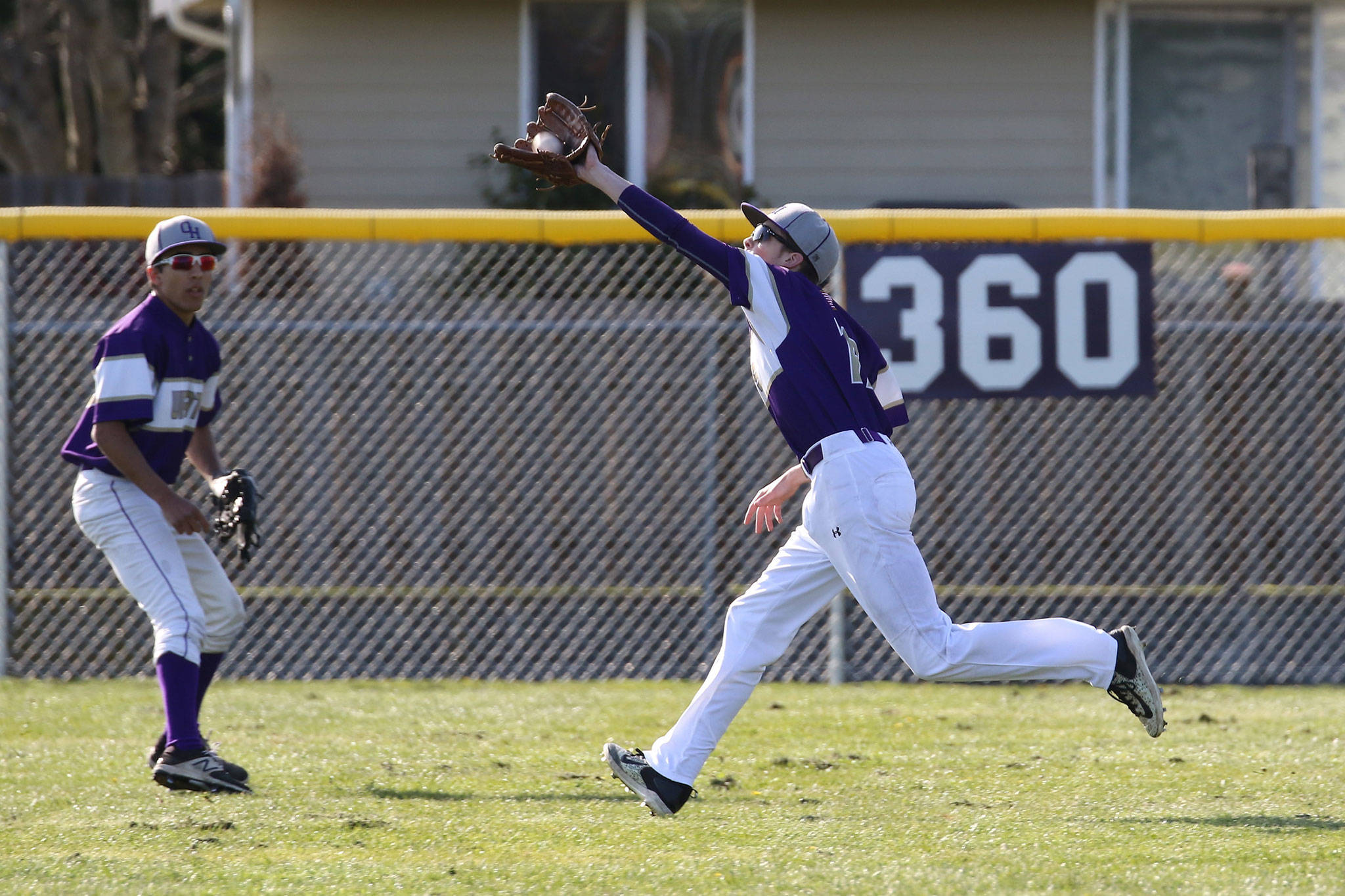 Oak Harbor center fielder Austin Boesch runs down a fly ball as Caleb Fitzgerald looks on in Tuesday’s game with Everett. (Photo by John Fisken)