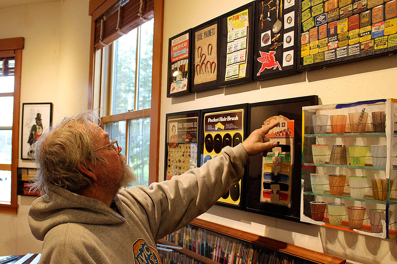Richard Marquis looks over the arrangement of his “Found Objects” installation at Bayview Corner’s Front Room Gallery. A Freeland glass artist with pieces in galleries worldwide, he’s also collected vintage advertising and other items. Photo by Patricia Guthrie/Whidbey News Group