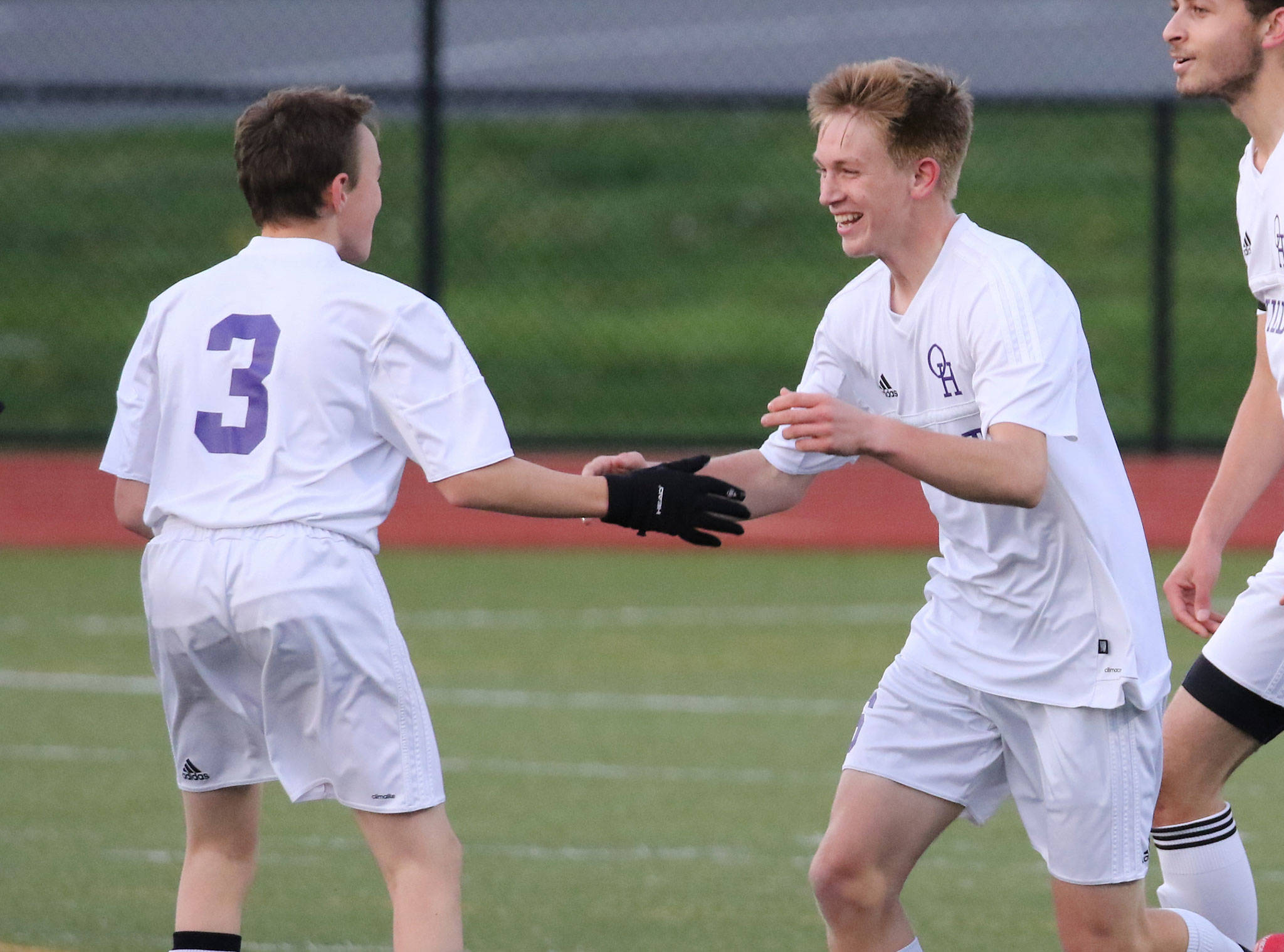 After scoring a goal, Nathan Merrill, center, is congratulated by teammate Alexander Johnston. (Photo by John Fisken)