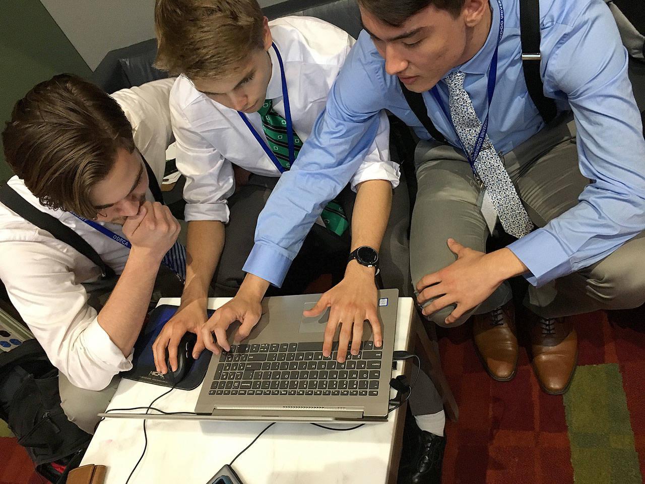 From left, Casey Towsley, Ben Gasper and Cullen Wood use their unique method to run a 15-minute hotel business simulation at the DECA international championship in Atlanta, Ga. The team was able to take first place in the last five seconds. Photo provided