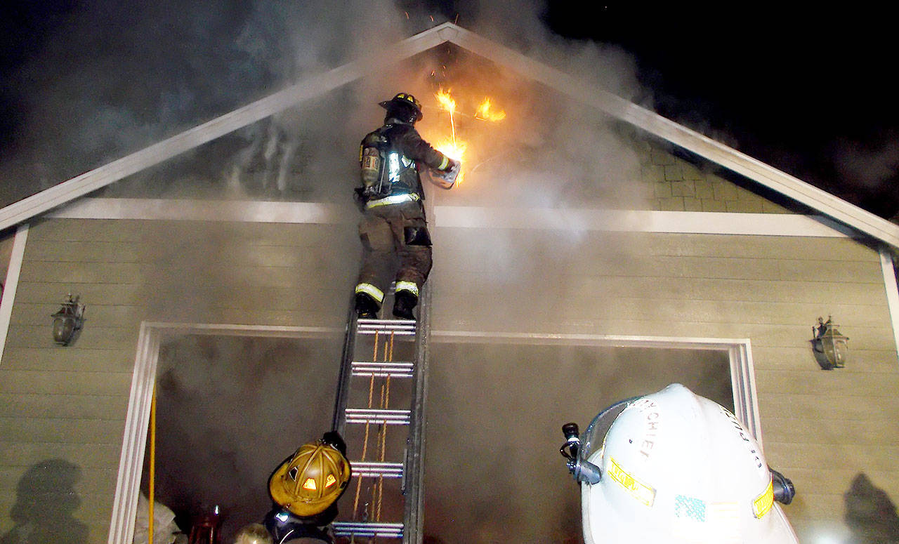 A firefighter from the Oak Harbor Fire Department vents the attic space during a structural fire around midnight on Monday. Photo provided