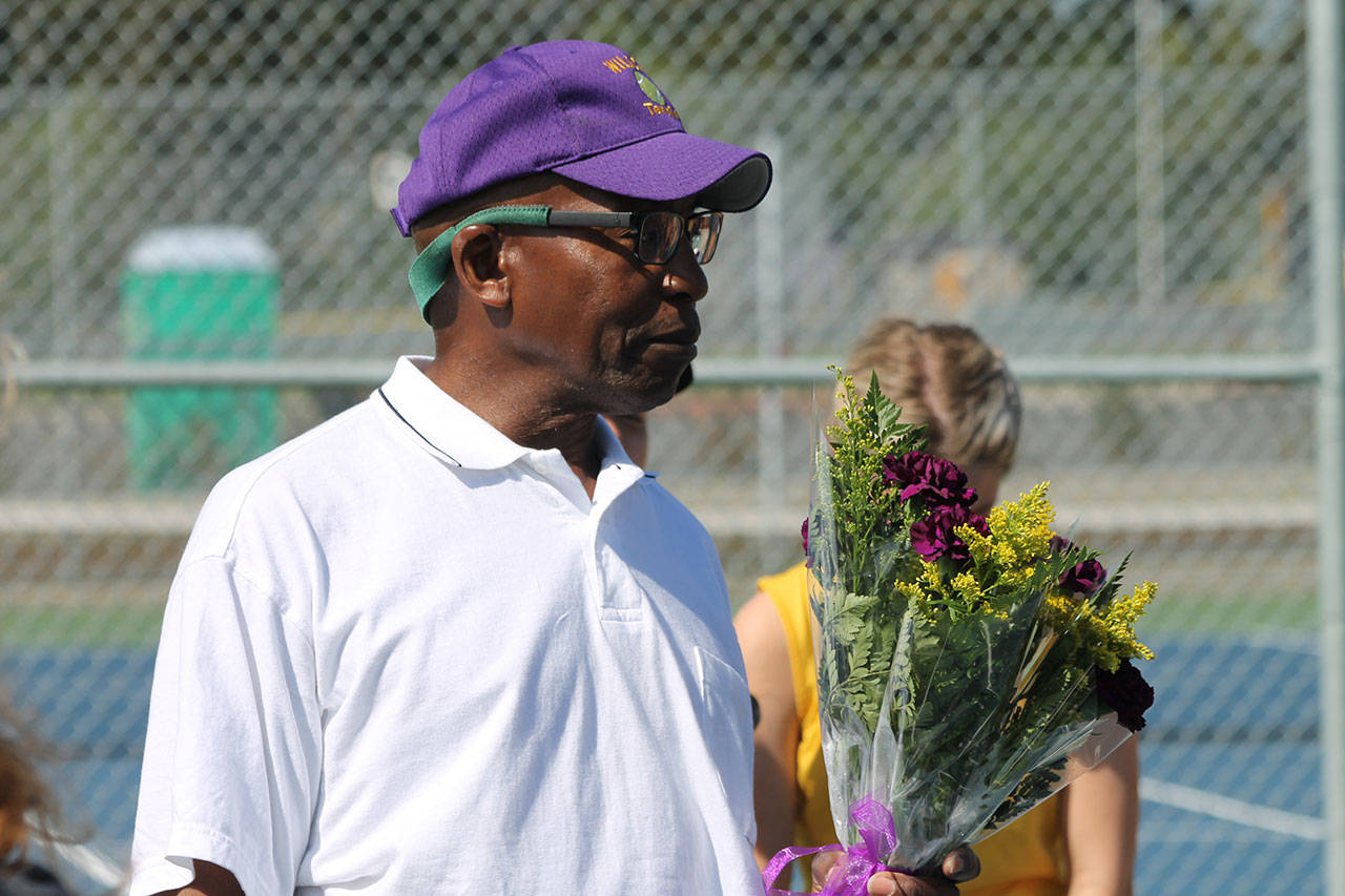 Oak Harbor coach Horace Mells is retiring this season after leading the OHHS tennis program for 21 years. Above he is holding flowers he is giving to his senior players in their final home match Wednesday. (Photo by Jim Waller/Whidbey News-Times)