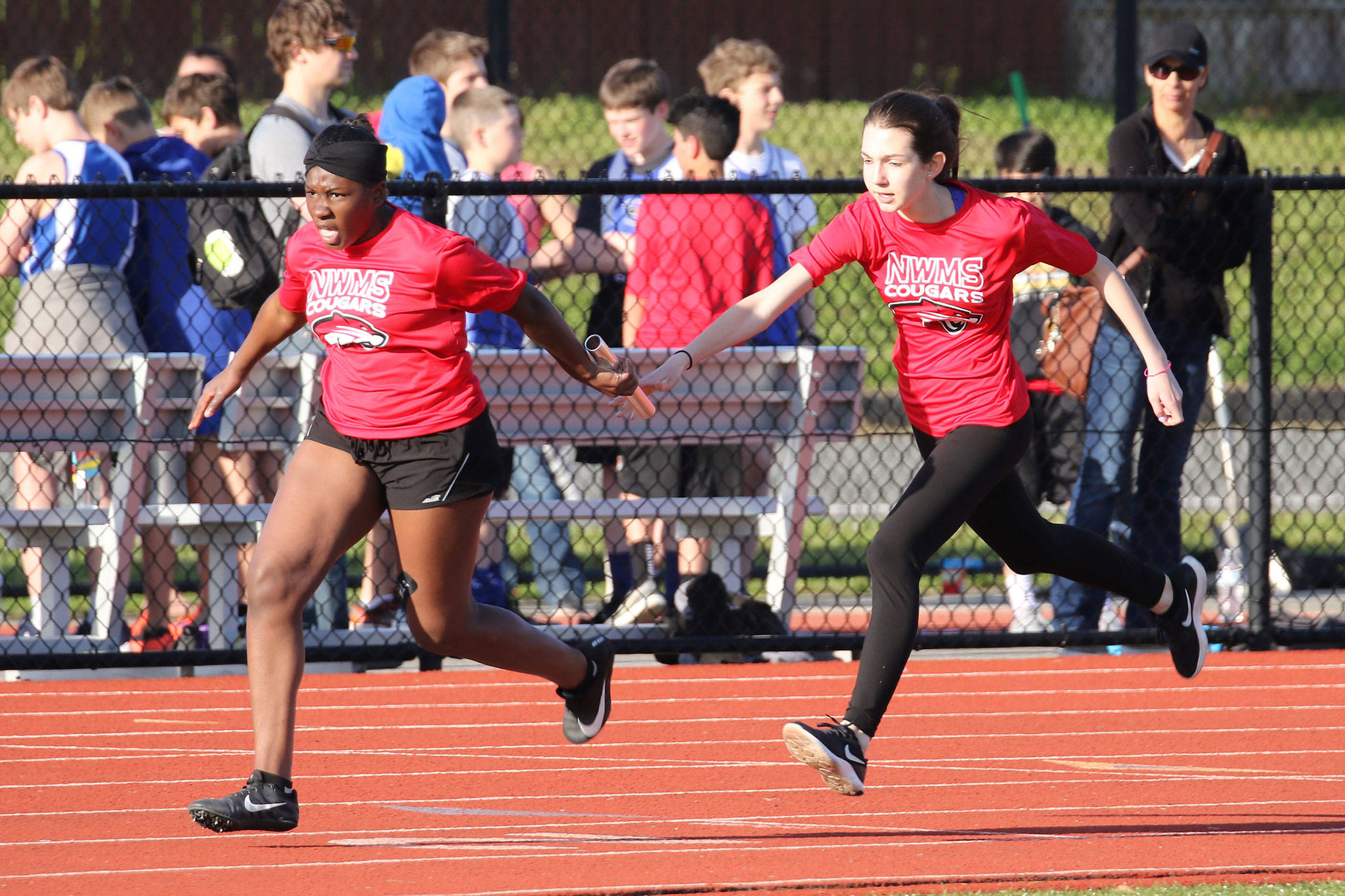 Anai Hardin, left, takes the baton from Alexis Kunze in the eighth-grade girls 4x100 relay Wednesday.(Photo by John Fisken)