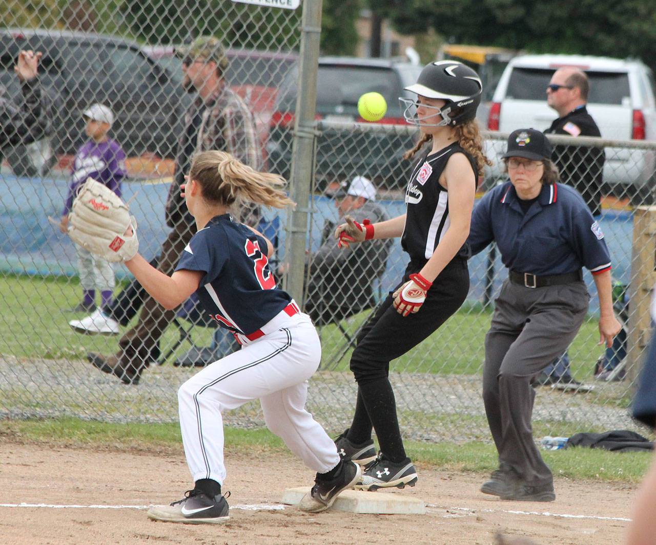 The ball gets away from South Skagit third baseman Ryan Holt, allowing Gwen Gustafson to head home for a run as umpire Rita Cline watches the play. (Photo by Jim Waller/Whidbey News-Times)