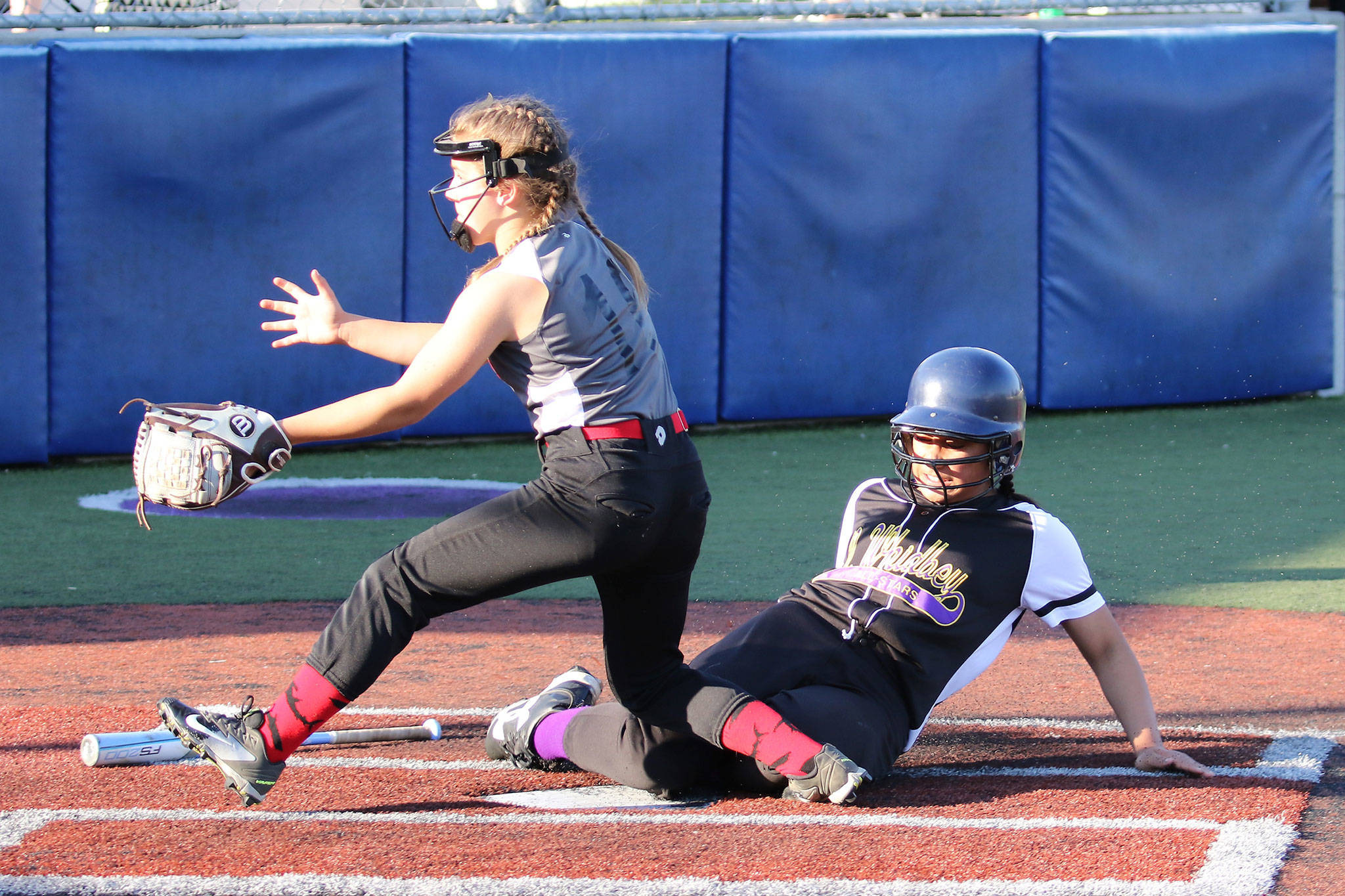 North Whidbey’s Loto Tupu slides safely into home while Central Whidbey’s Chloe Marzocca waits for the throw. (Photo by John Fisken)