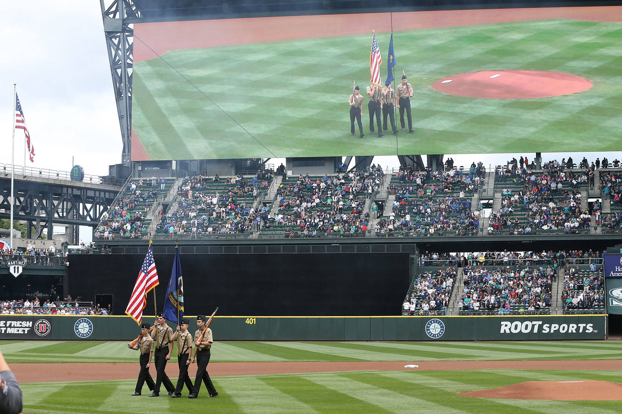 The Oak Harbor High School color guard is displayed on the video screen at Safeco Field Sunday. (Photo by John Fisken)