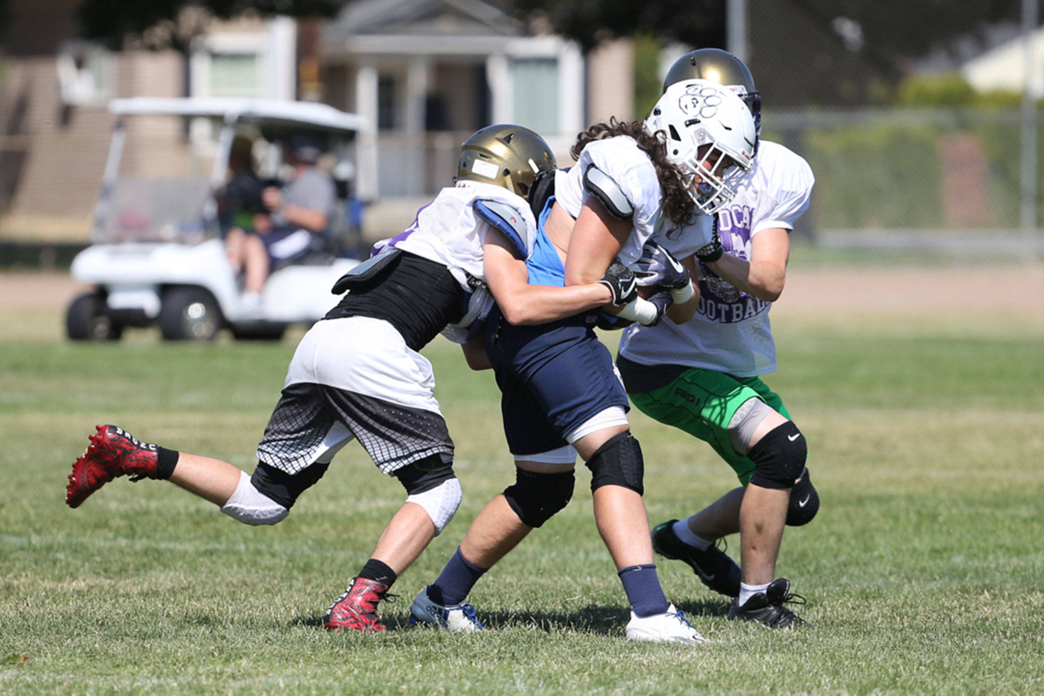 Two Wildcats bring down an opposing running back during a scrimmage Monday at the Wenatchee team camp. (Photo by John Fisken)