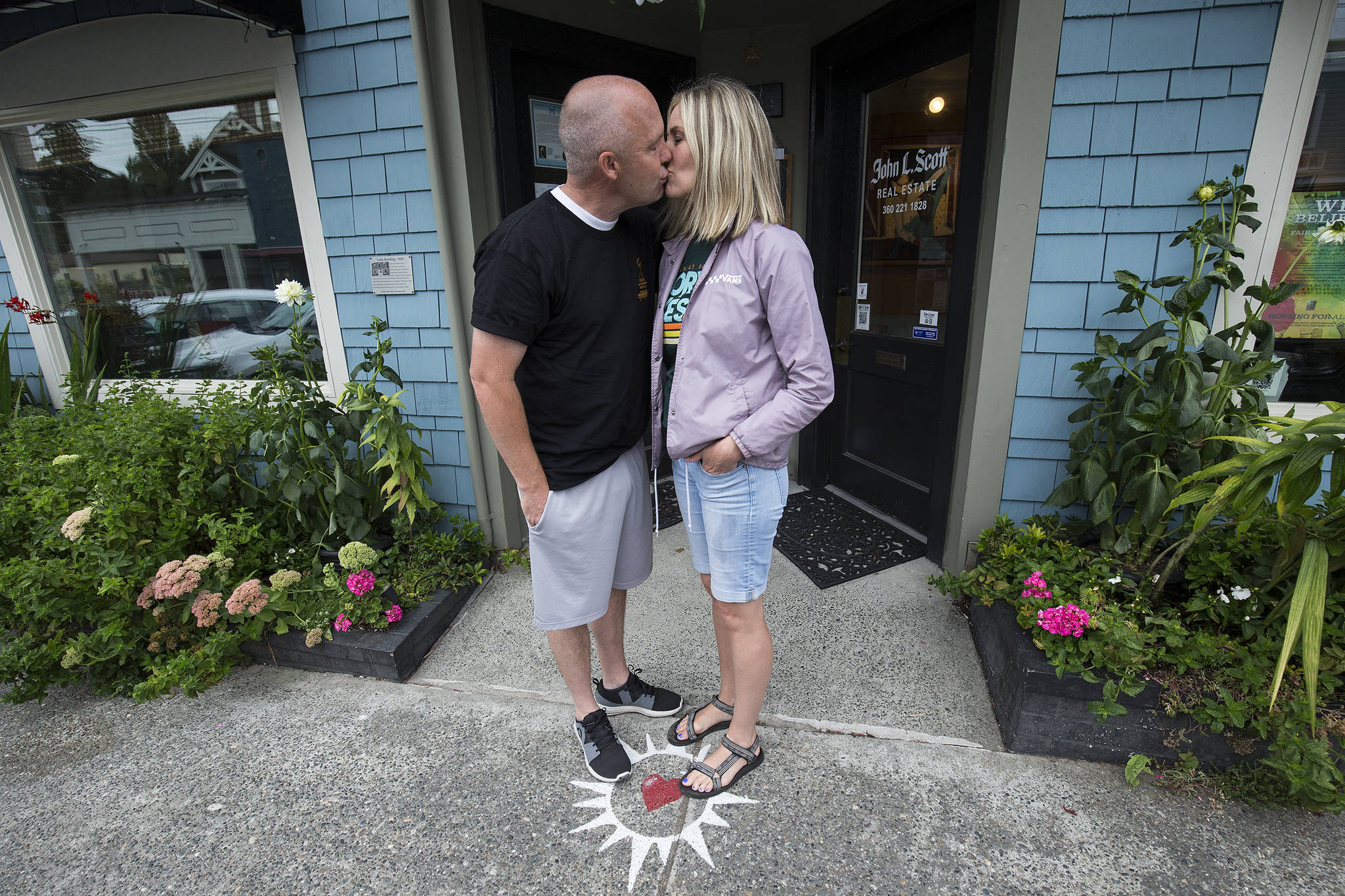 Photos by Andy Bronson / The Everett Herald&lt;em&gt;&lt;/em&gt;                                &lt;em&gt;Theron Murphy, of Orem, Utah, kisses his wife, Jody, in front of the John L. Scott Real Estate office in Langley. People stand on the sidewalk on the heart below the “kissing ball,” kiss, then make a hash mark on the chalkboard. The office keeps a tally and posts the monthly and yearly count.&lt;/em&gt;