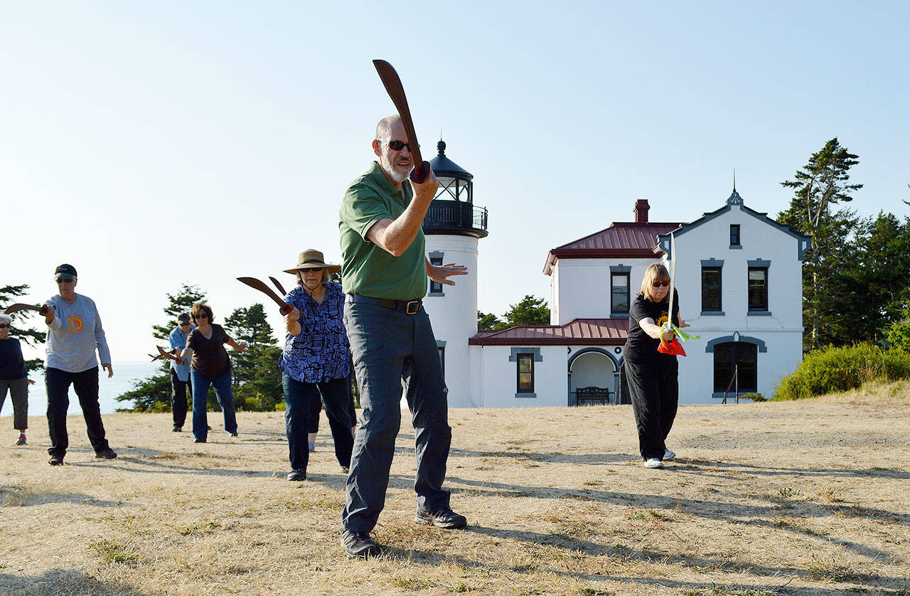 Frank Worster, front, holds out his wooden saber during a t’ai chi workshop Tuesday night at Fort Casey. Lynne Donnelly, right, started taking the class to the state park because there wasn’t enough room in her Freeland studio for sword swinging. Photo by Laura Guido/Whidbey News Group