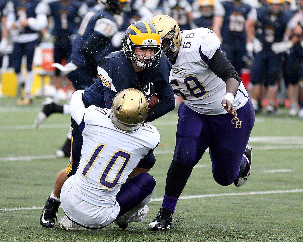 Left: In last year’s state playoffs, Mac Carr brings down a Bellevue ball carrier as De’Andre Bennett closes in. The WIAA will use committees to seed the teams in this year’s state tournament. (Photo by John Fisken)