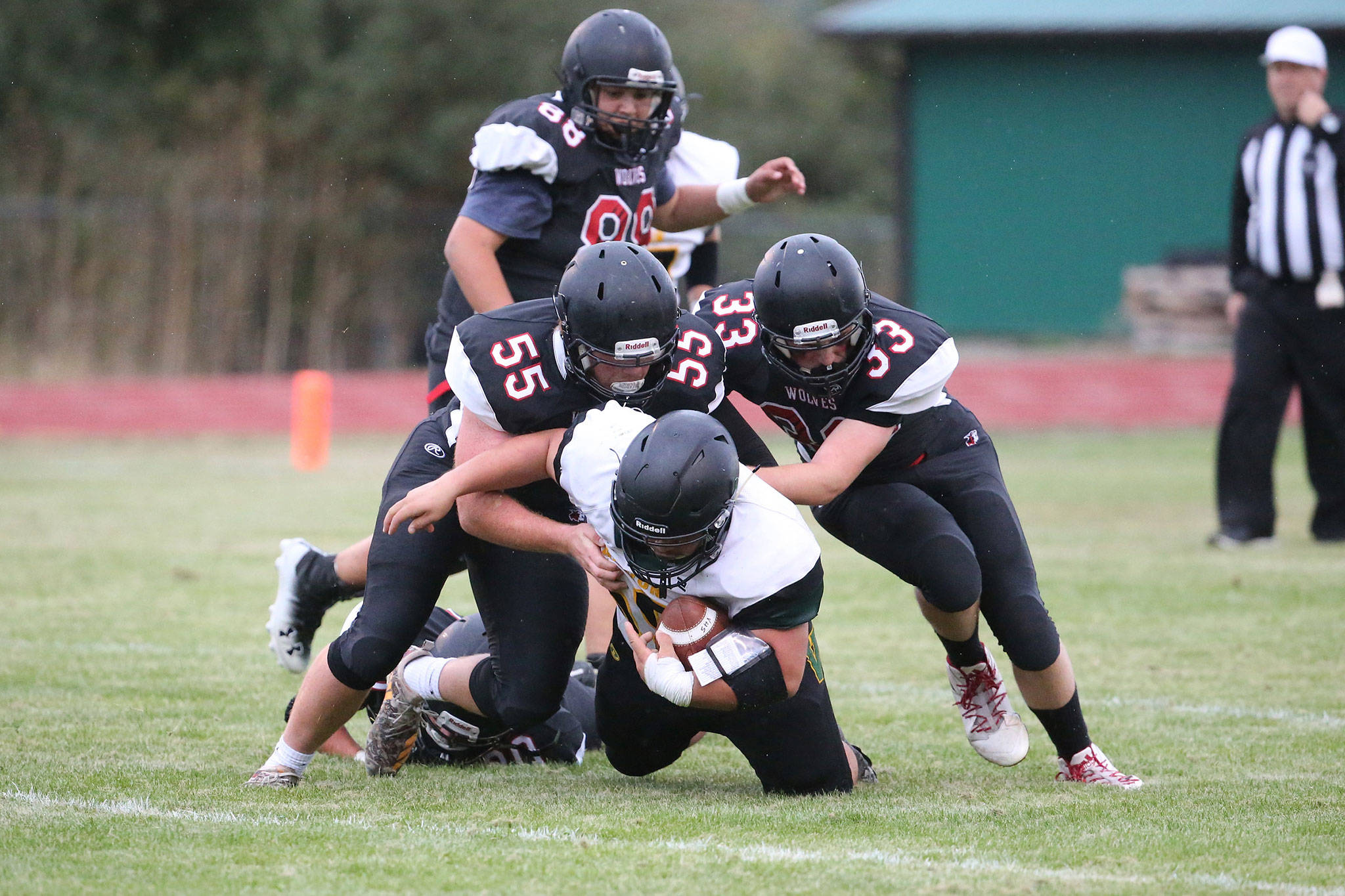 Coupeville defenders Alex Turner (55) and Gavin Knoblich (33) smother a Vashon Island ball carrier as Isaiah Bittner closes in.(Photo by John Fisken)