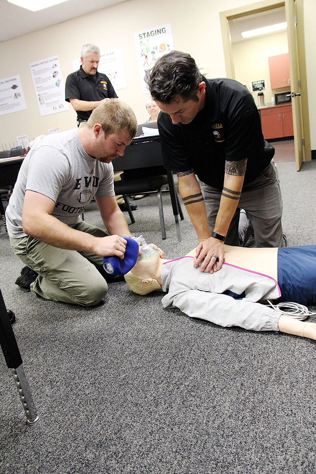 Kole Kellison, left, and Capt. Jerry Helm perform a demonstration with Central Whidbey Island Fire and Rescue’s new high-tech CPR dummy. Fire commissioners watched a display of the dummy’s simulated vitals change as the two provided treatment. Photo by Laura Guido/Whidbey News-Times