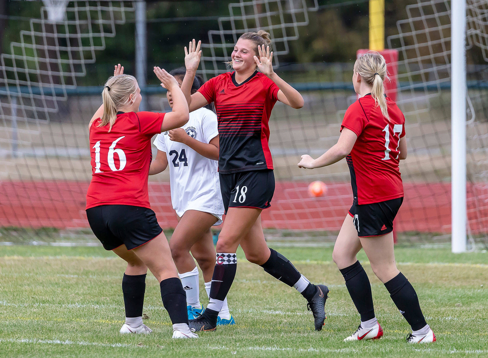 Avalon Renninger (16), Lindsey Roberts (18) and Audrianna Shaw (17) celebrate a Coupeville goal. (Photo by John Fisken)
