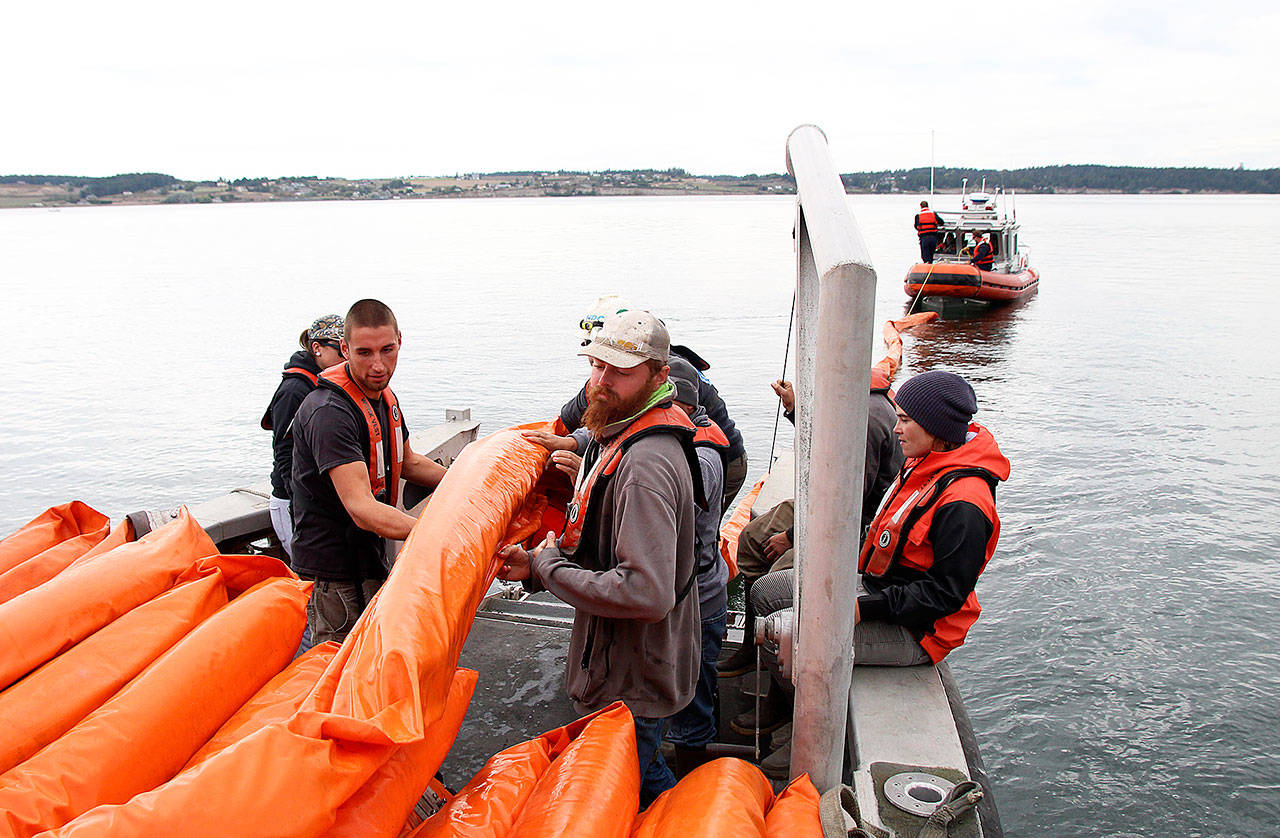 Jeremiah Tumulty, left, and Brandon Andrews, help deploy an oil boom last Friday afternoon during a training exercise. Central Whidbey Island Fire and Rescue personnel assisted from the district’s boat. Photo by Laura Guido/Whidbey News-Times
