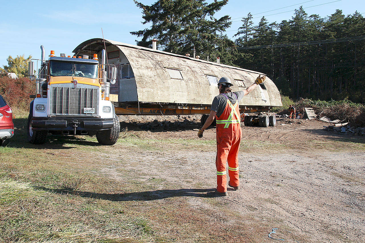Photo by Laura Guido/Whidbey News-Times                                Cody Robertson directs the truck driver carrying a Quonset hut that PBY Museum Foundation researchers believe is the last remaining one still in its original configuration from WWII Homoja Housing Program.