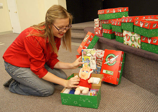 Photo by Maria Matson/Whidbey News Group.                                Drop-Off Coordinater Katelyn Morehead shows one of the many boxes that have already been packed at the Church on the Rock in Oak Harbor.