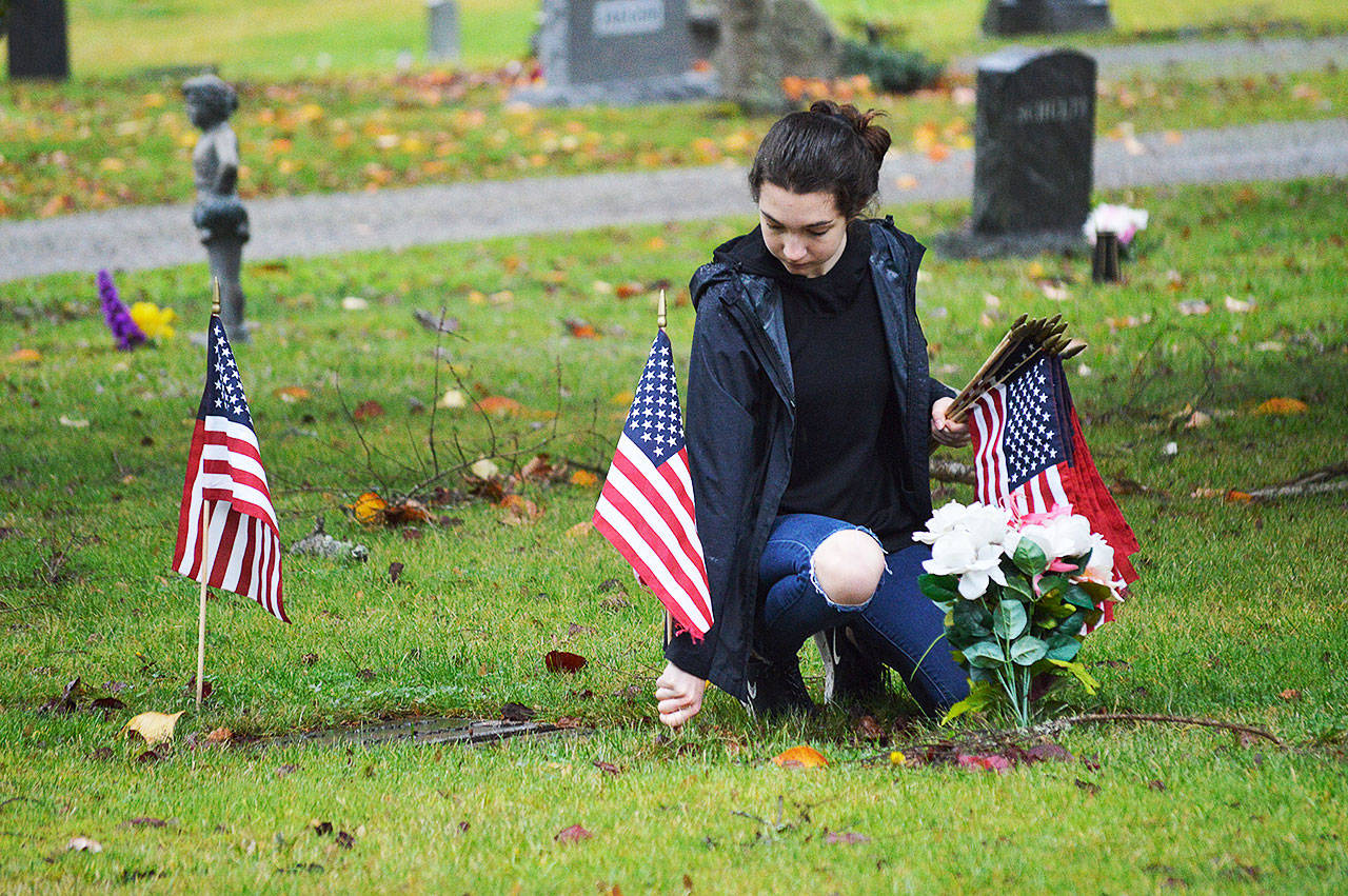 Alexis Kunze, a freshman NJROTC member, plants a flag near the grave of a deceased veteran Saturday at Maple Leaf Cemetary. Photo by Laura Guido/Whidbey News-Times