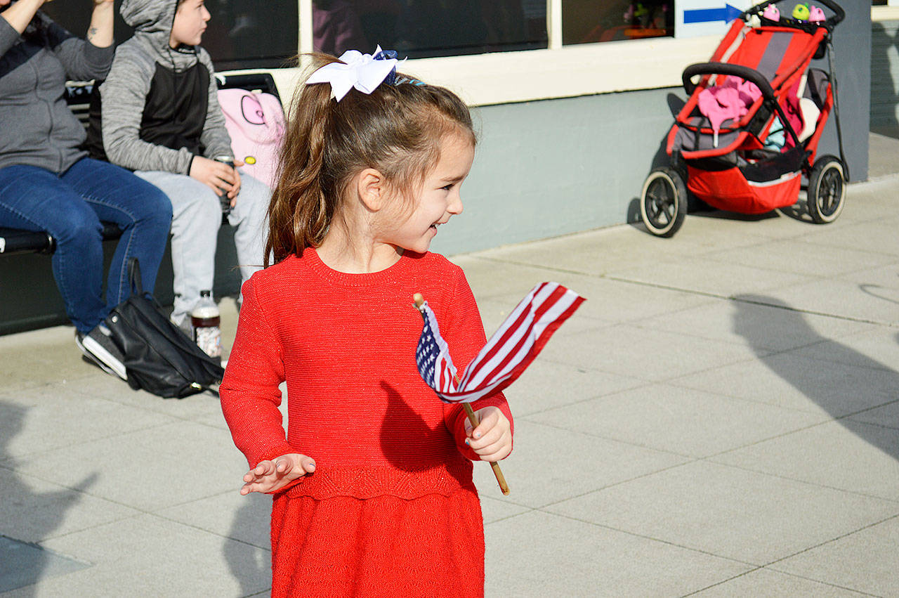 Photo by Laura Guido/Whidbey News-Times                                Reese Thomason waves her little American flag as the parade’s procession goes past her Monday afternoon at the Oak Harbor Veterans Day Parade on Pioneer Way.