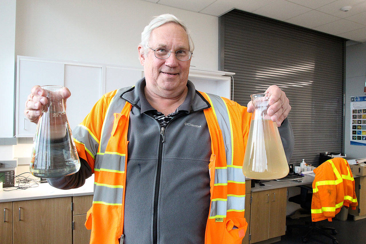 Photo by Jessie Stensland / Whidbey News-Times                                Brett Arvidson, project manager for the sewage treatment plant, holds flasks of treated water before and after the plant started.